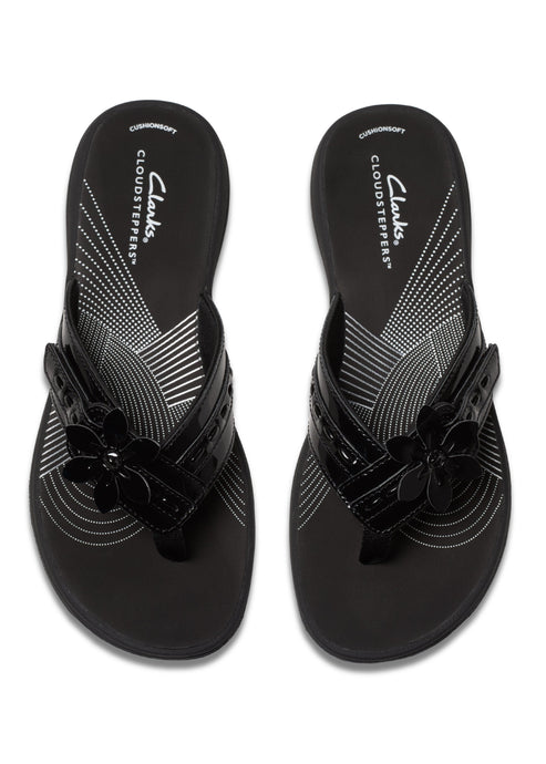 Pair of black CLOUDSTEPPERS flip flops with glossy straps and flower embellishments.