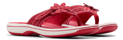 A pair of red sandals with a white sole and a flower embellishment.