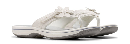 Two white flower-decorated sandals with white straps and gray soles.
