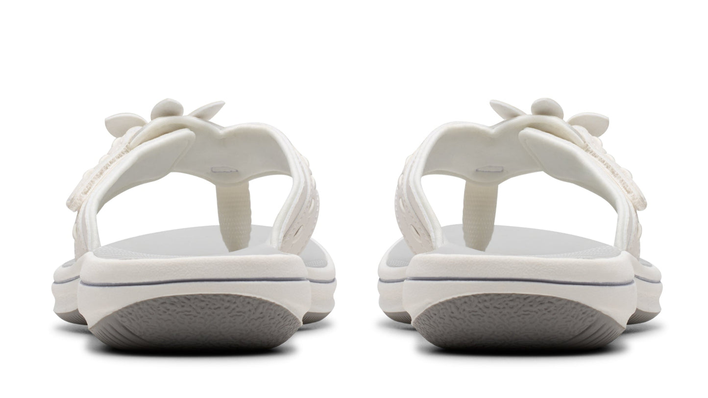 A pair of white, wedge thong sandals showing the back.