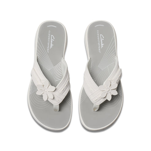 Two white flip-flops with flower detail on a gray insole.