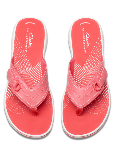 A pair of coral-colored flip flops with a white sole and circular patterns near the toe.