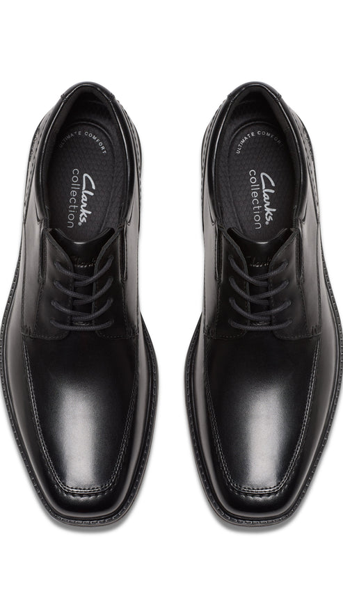 Overhead view of a pair of black leather dress shoes with laces and visible "Clarks collection" logo inside.