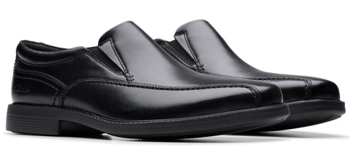 Two black, leather slip-on dress shoes with thick, black soles.