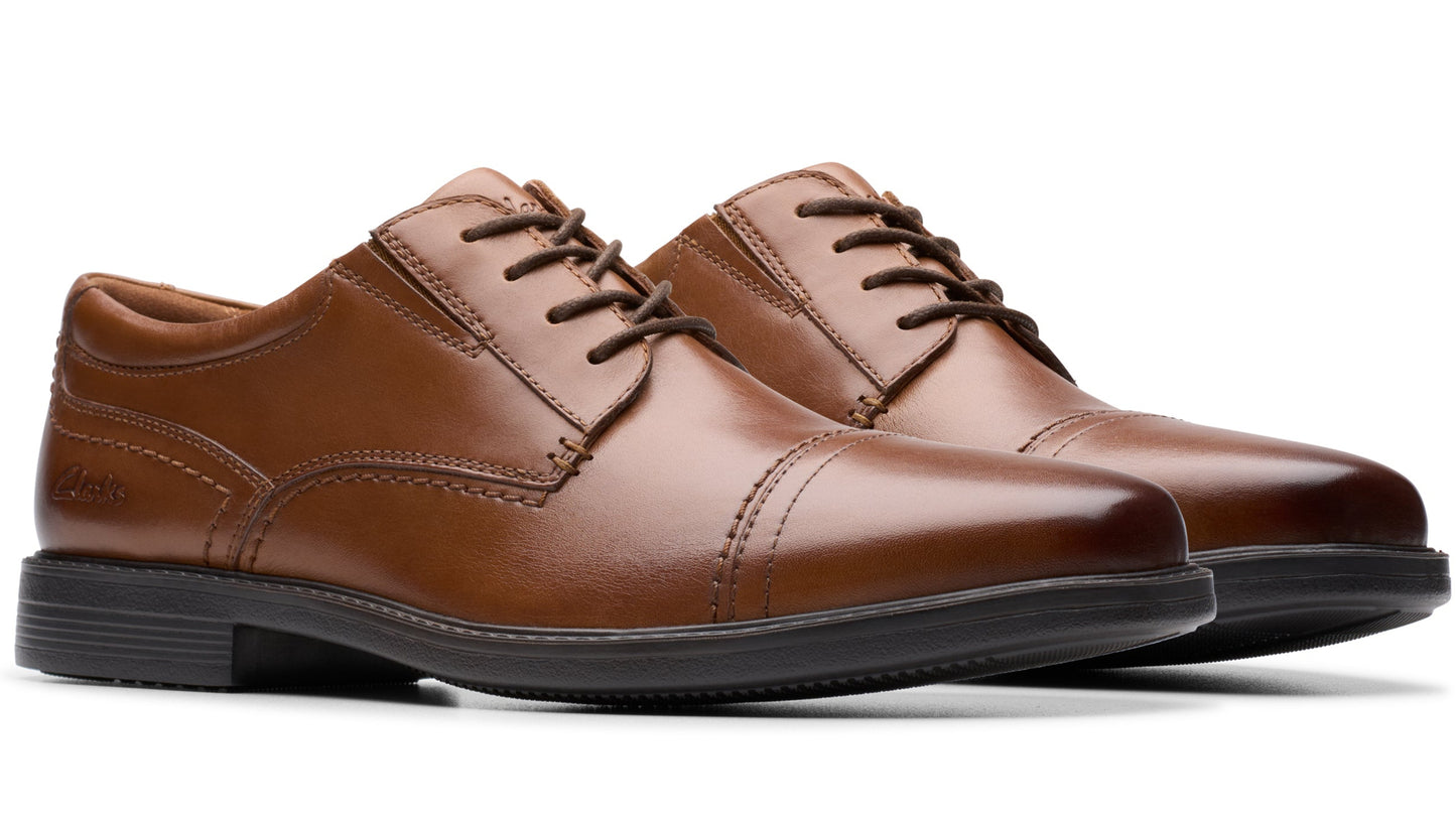 Pair of brown leather cap toe dress shoes with black soles and laces.