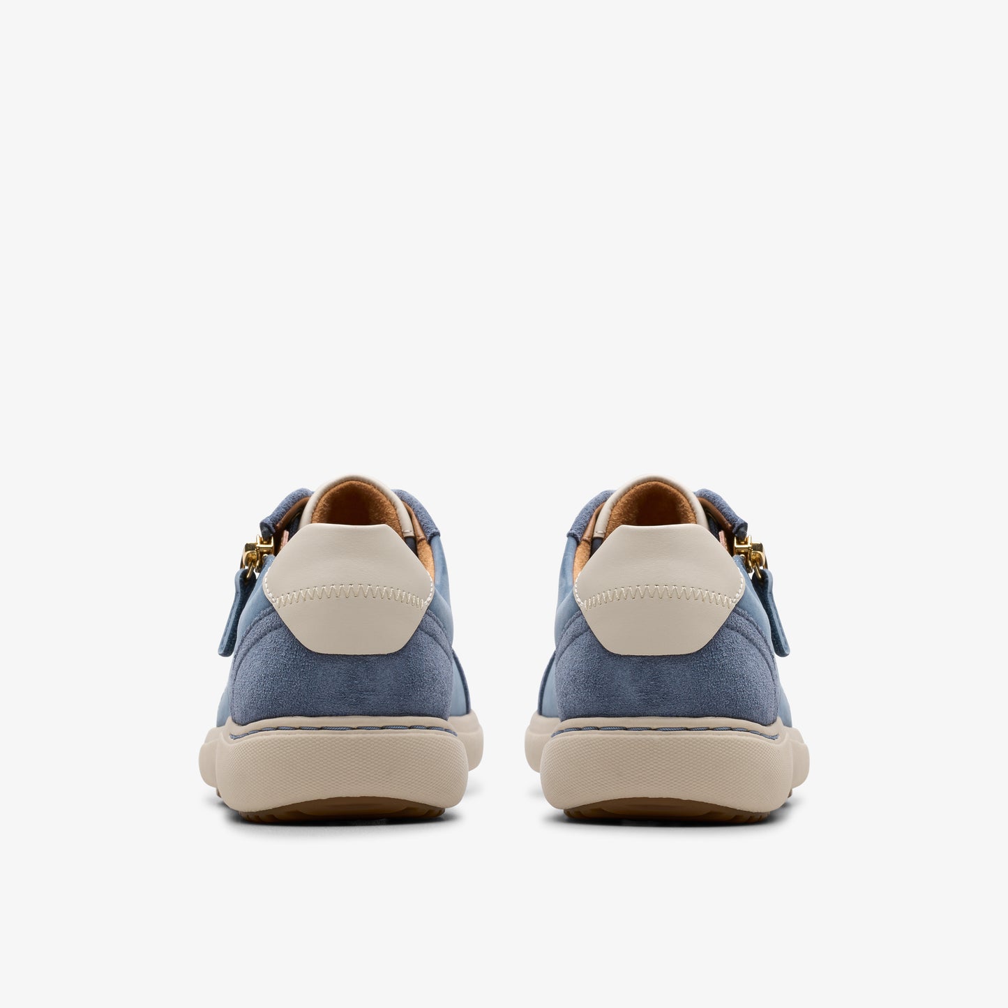 Rear view of two blue suede sneakers with off-white heel patches and tan soles.