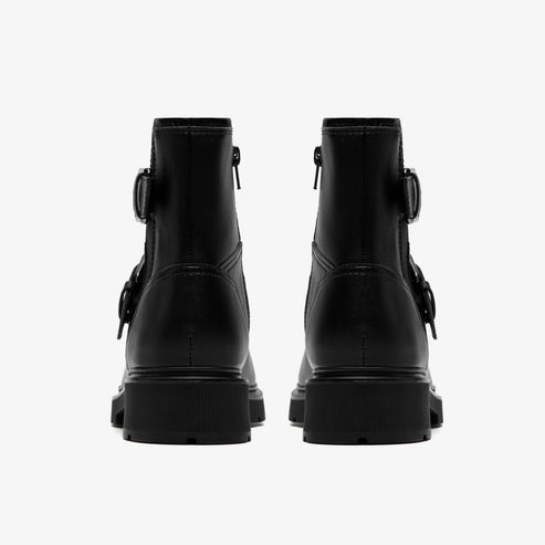 A pair of black, leather ankle boots, with buckles and visible zipper on the sides, and a thick lug sole, as viewed from the rear.