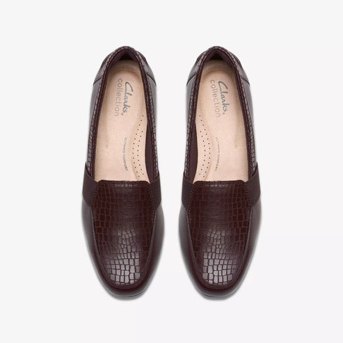 Pair of brown leather slip-on shoes with alligator texture.