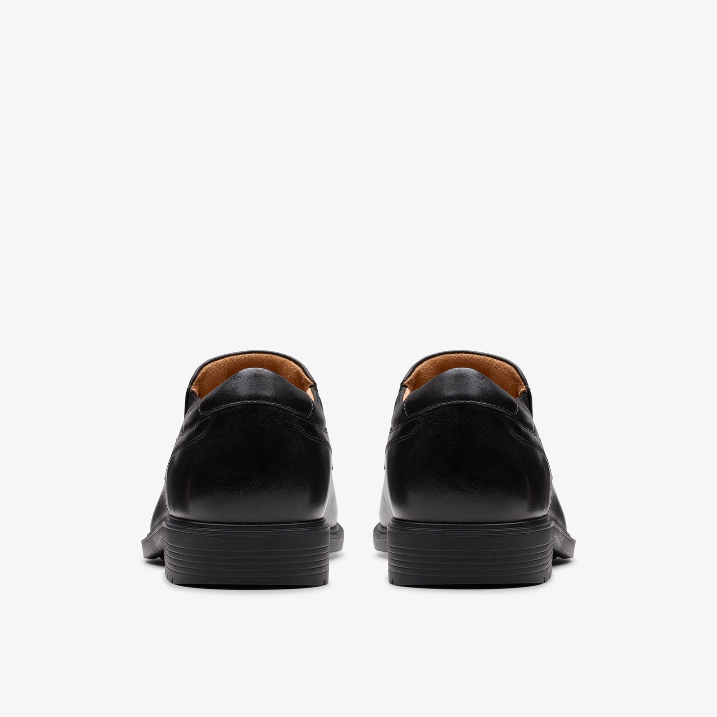 Back view of two black leather dress shoes with rounded toes and flat heels.
