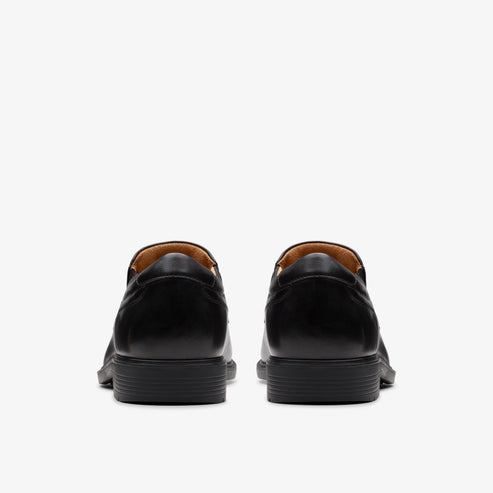 Back view of two black leather dress shoes with rounded toes and flat heels.
