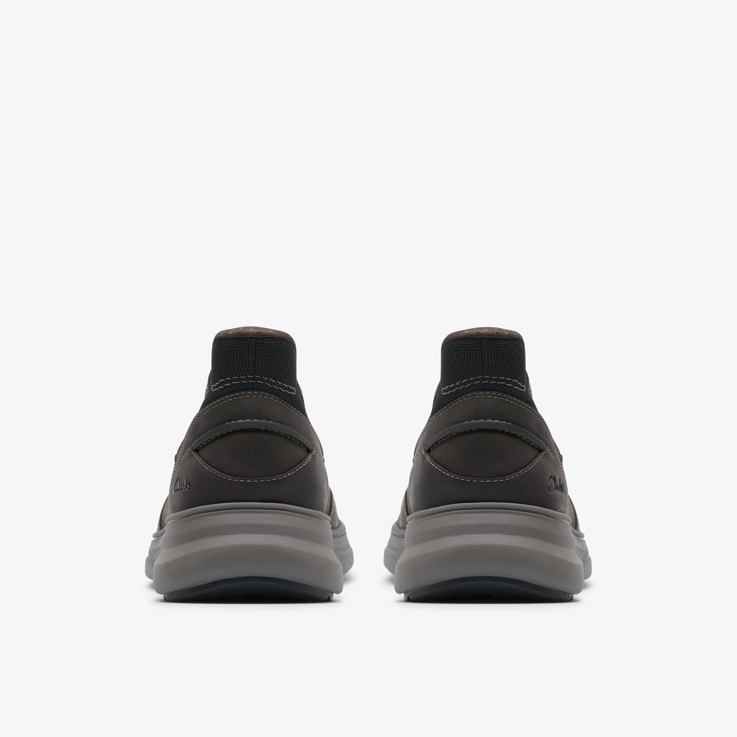 Pair of sock-like dark grey athletic shoes with thick grey soles, rear view.
