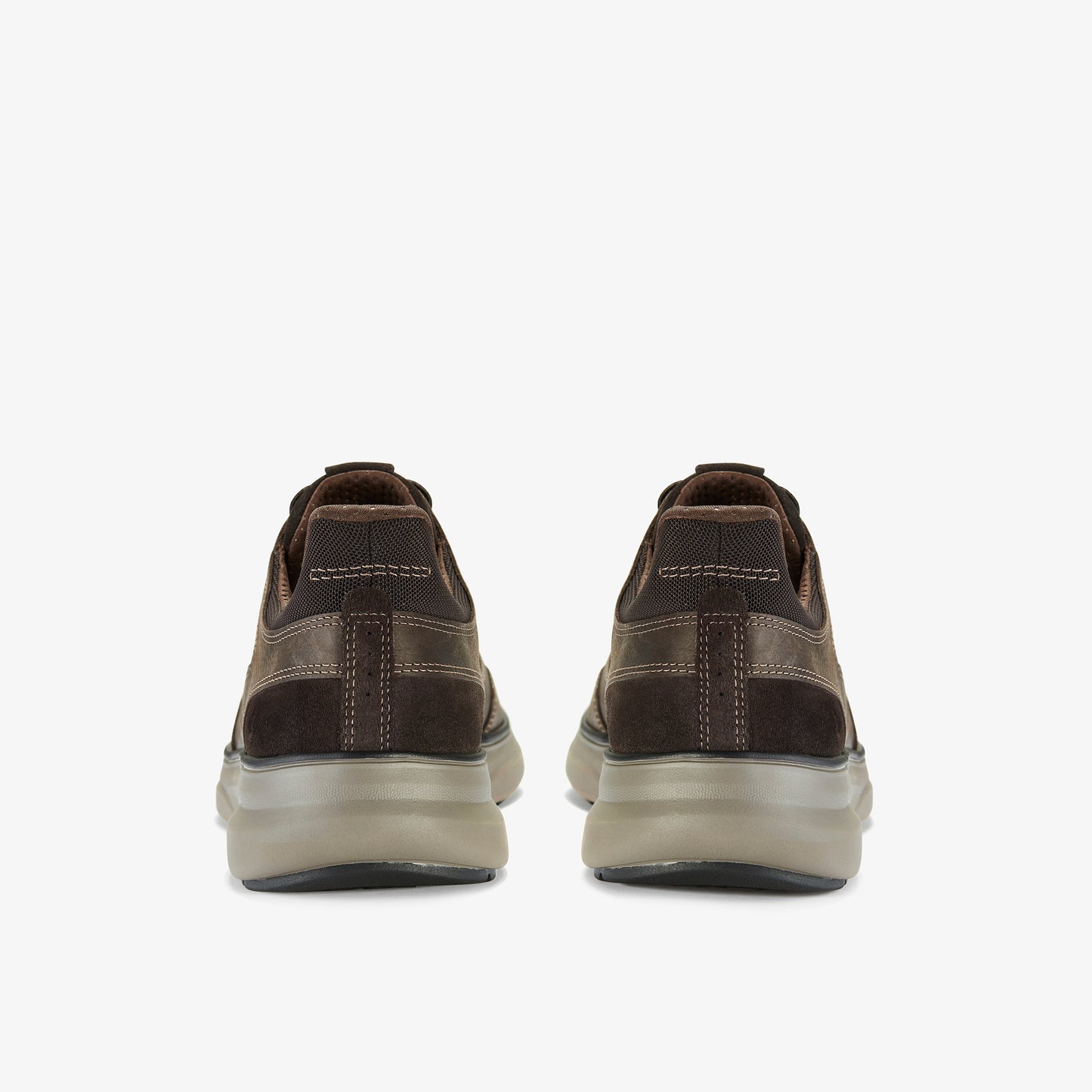 Rear view of a pair of brown suede casual shoes with decorative stitching and thick, translucent soles.