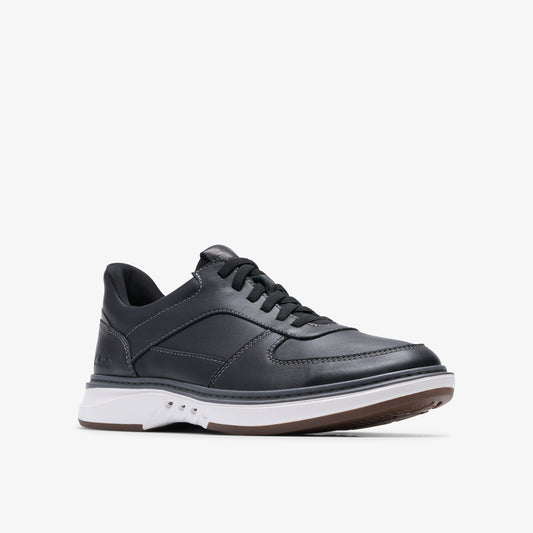 A black leather sneaker with black laces and a thick white sole with a brown outsole.