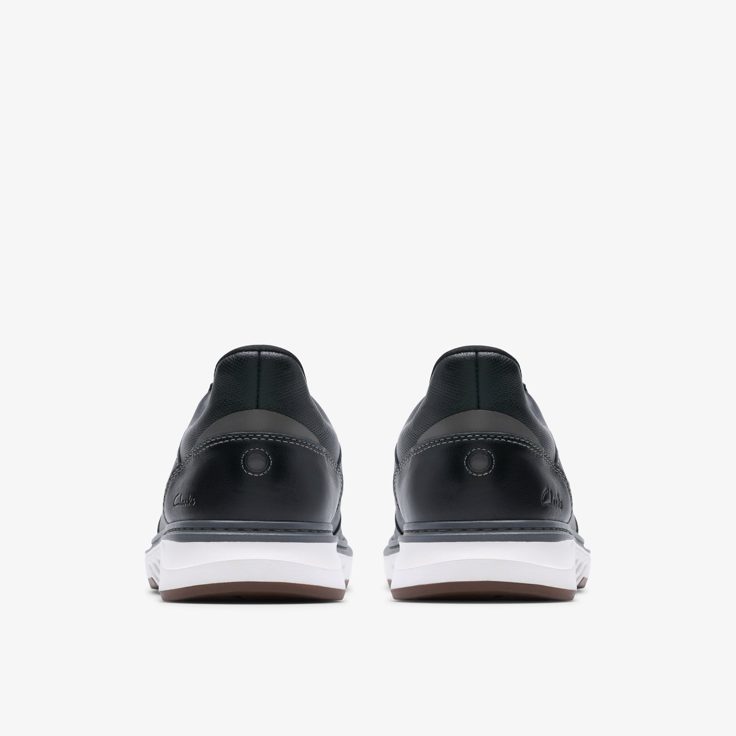 Two low-top black shoes with thick white soles, back view.