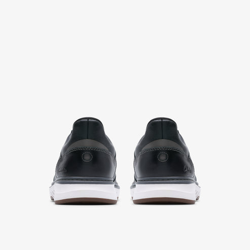 Two low-top black shoes with thick white soles, back view.