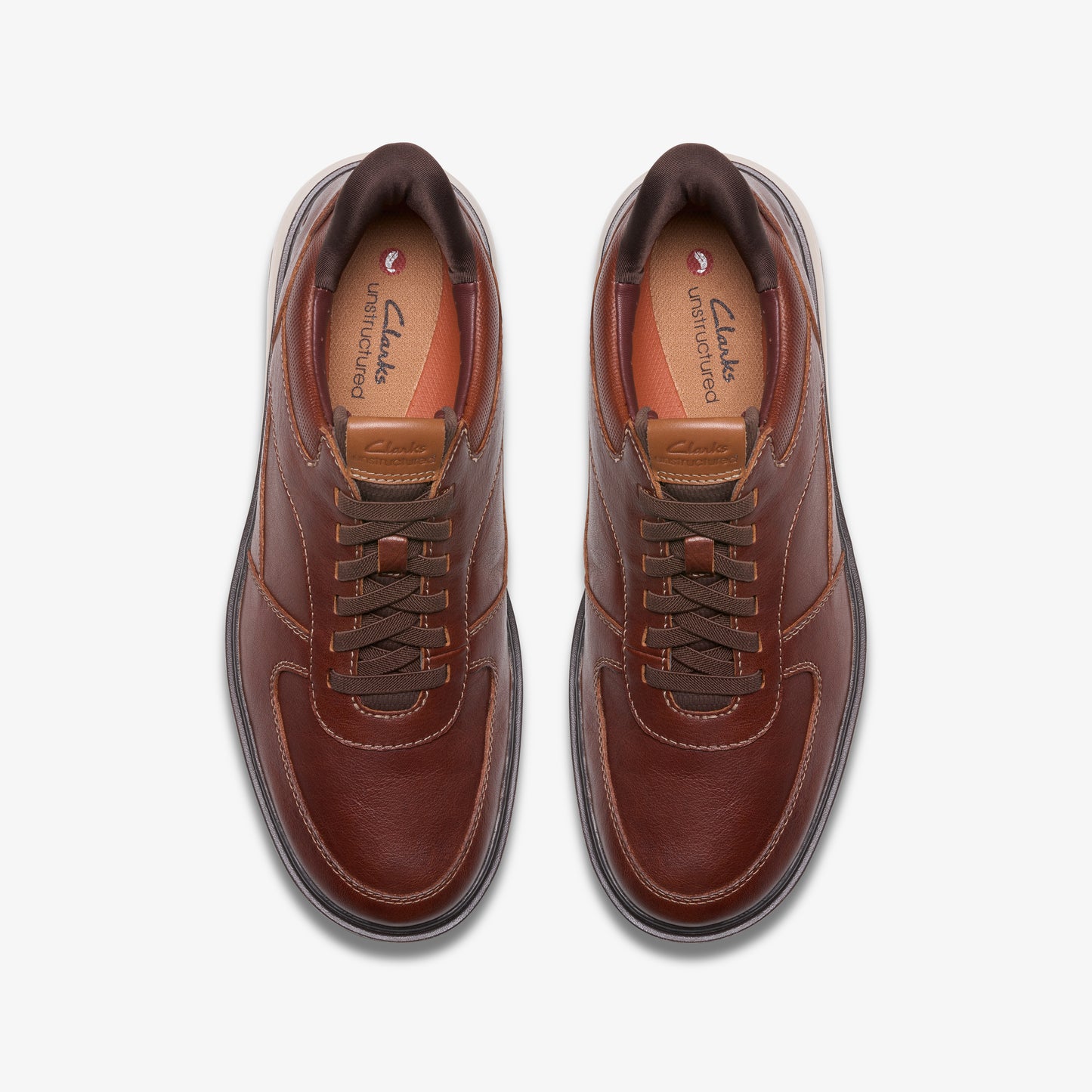 Overhead view of brown leather sneakers with brown laces and padded tan insoles.