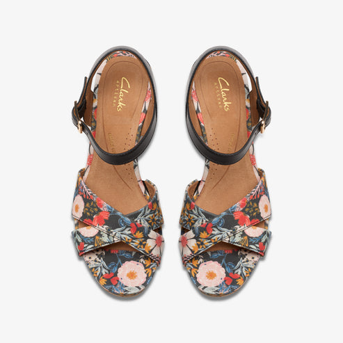 Overhead shot of floral print heeled sandals with black ankle straps.