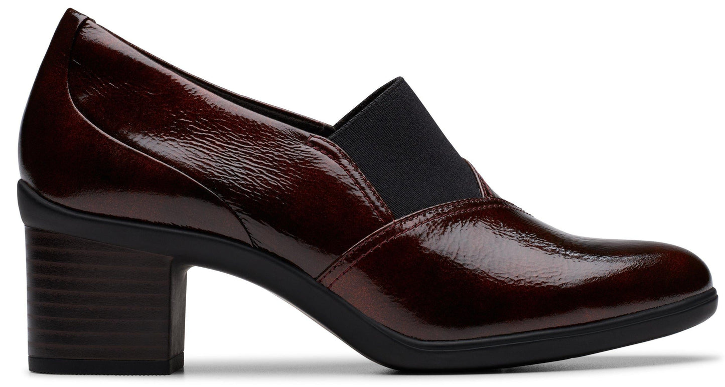 Patent leather burgundy heeled shoe with a rounded toe and a black elastic side panel.