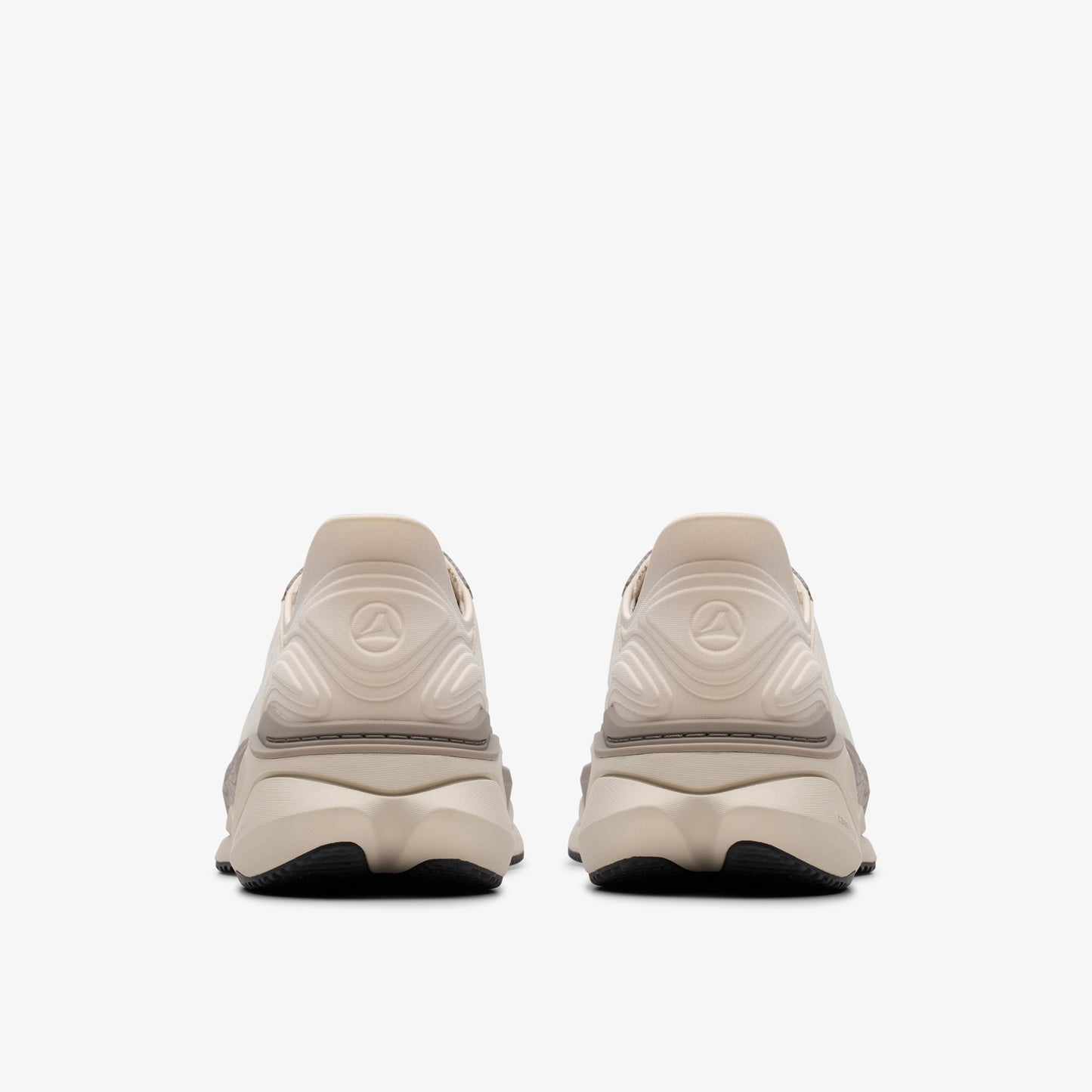 Two identical sneakers with cream-colored uppers and black soles are seen from the rear.
