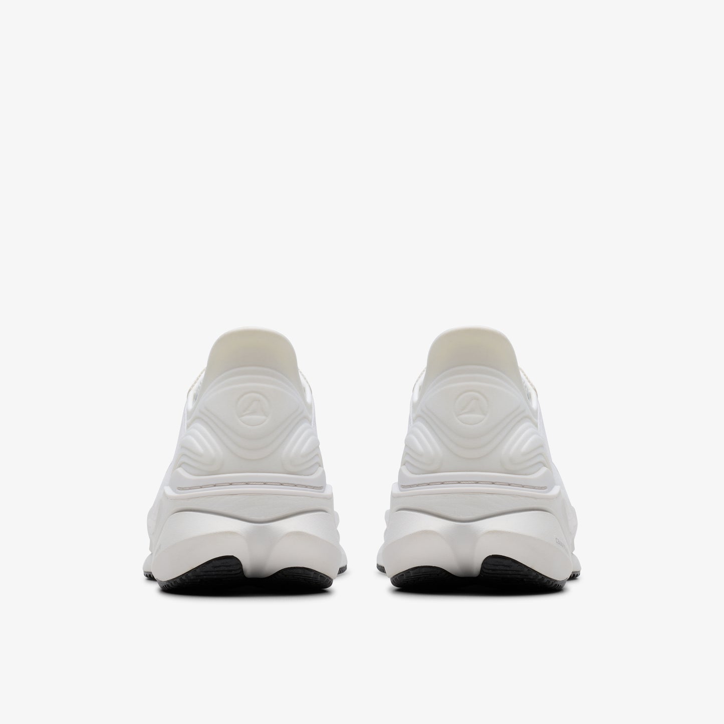 Two white running shoes with black soles facing away from the viewer.