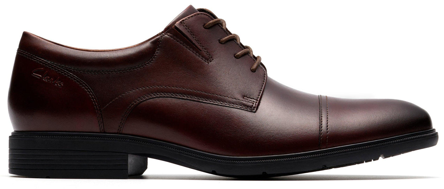 A dark brown leather cap-toe dress shoe with a black sole.