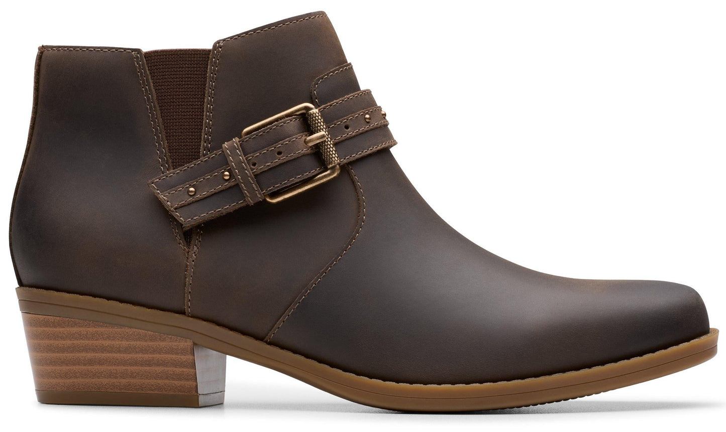Side-view of a brown leather ankle boot with elastic gusset, a strap with gold buckle, and a low heel.