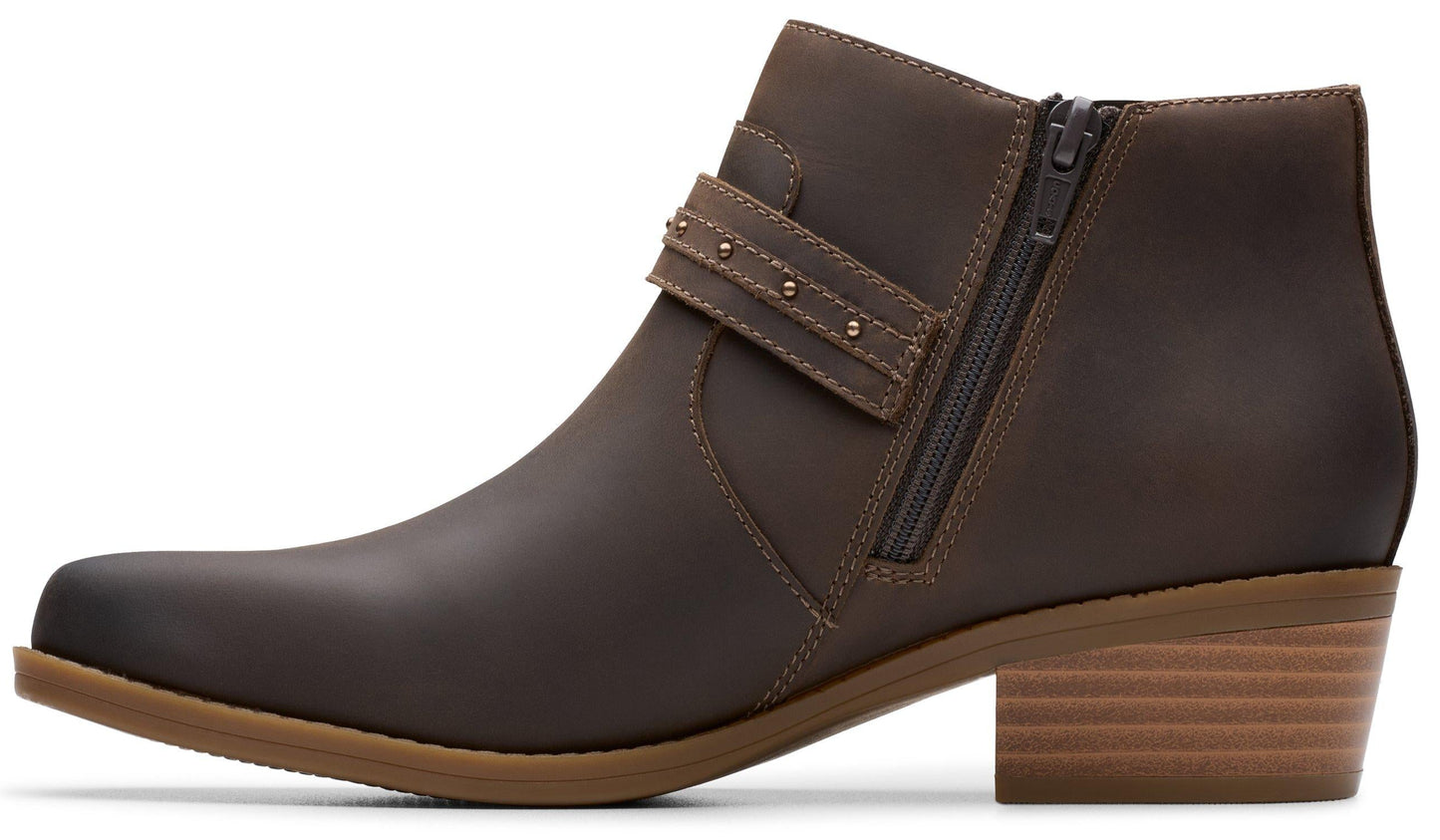 Brown leather ankle boot with block heel, side zipper, and studded strap.