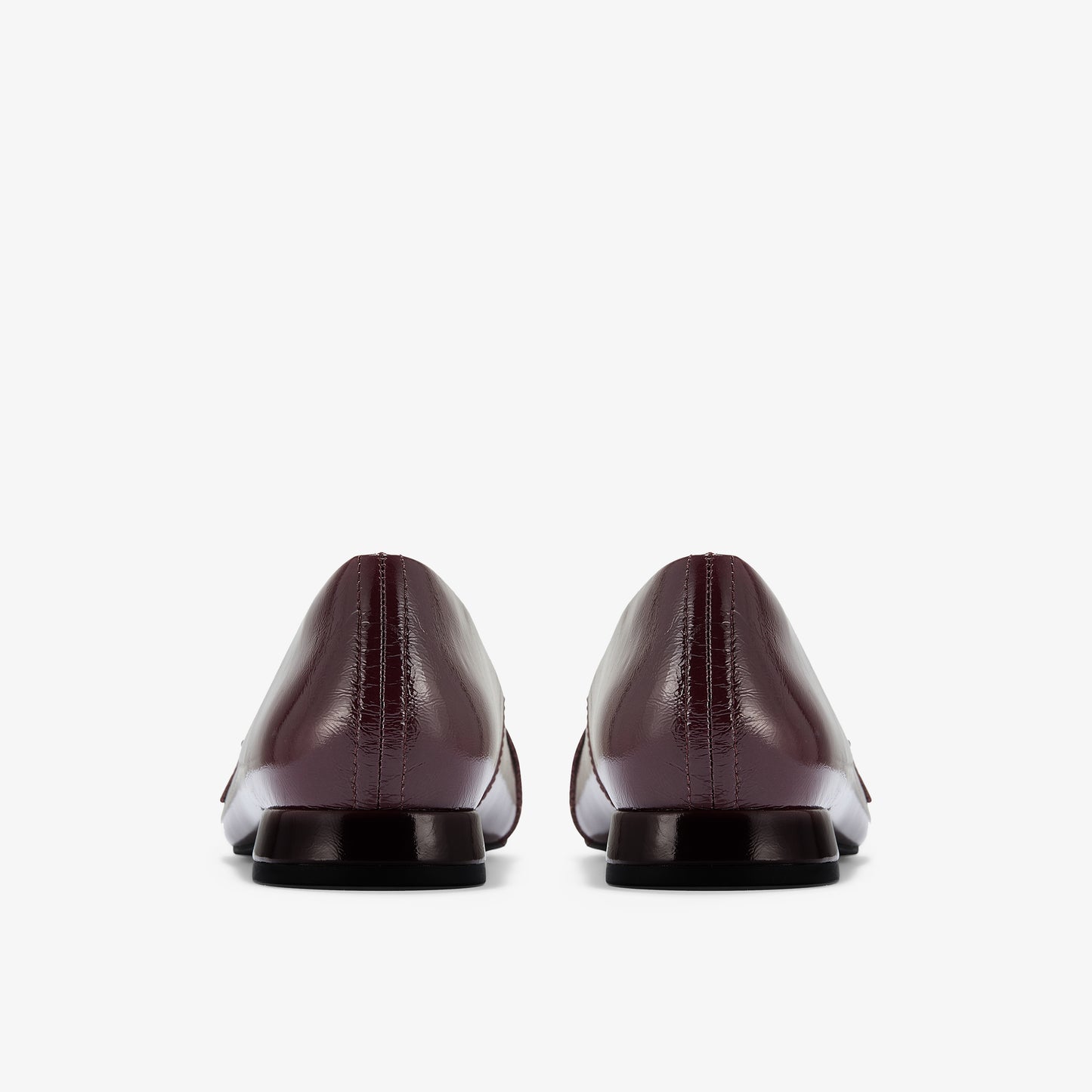 Rear view of a pair of dark red, leather dress shoes with a square heel.