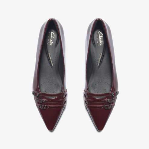 Pair of shiny, wine-colored, pointed-toe dress flats with three horizontal straps at the toe.