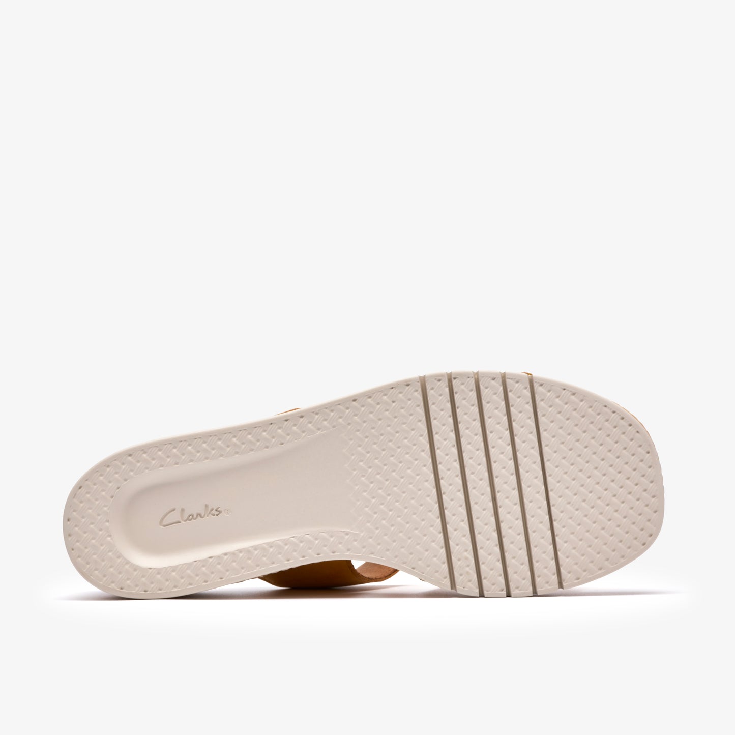 Bottom view of light-colored sole of flat sandal with raised parallel bars.