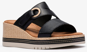 Black sandal with wedge heel, multiple straps, and circular detail.