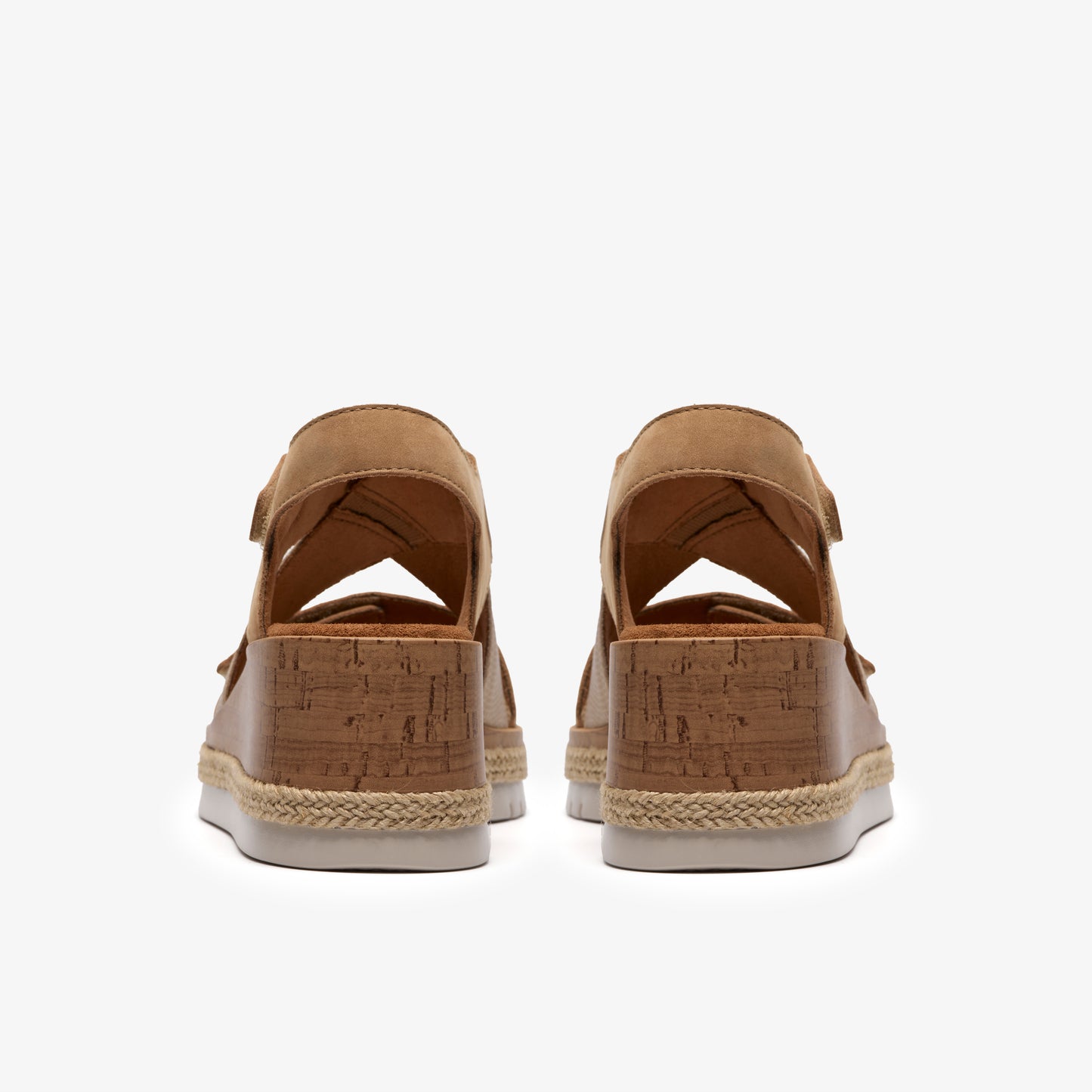 Pair of espadrille wedge sandals with light brown leather, cork platform, and white sole.