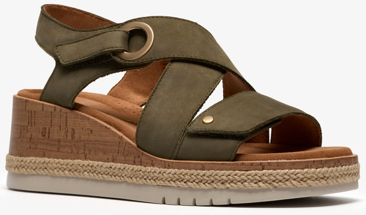 Olive green wedge sandal with crisscross straps, velcro heel strap, decorative gold ring and button, cork and jute midsole, and white ridged outsole.