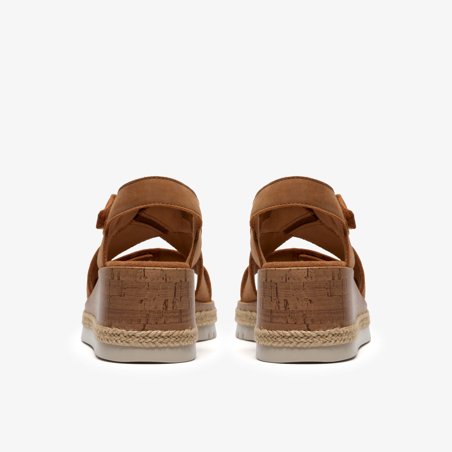 Pair of brown heeled sandals with cork bottoms, viewed from the back.
