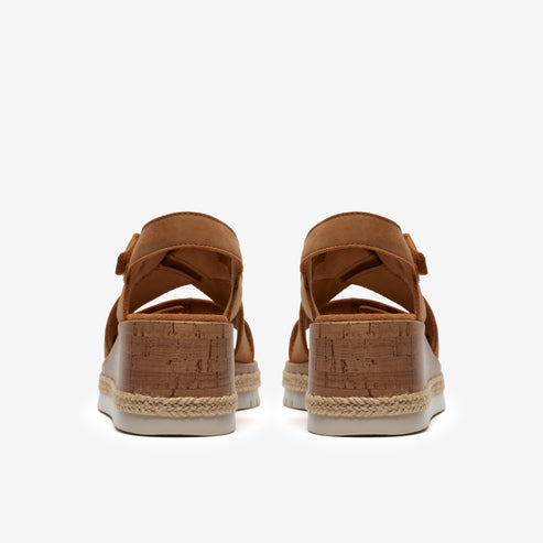 Pair of brown heeled sandals with cork bottoms, viewed from the back.
