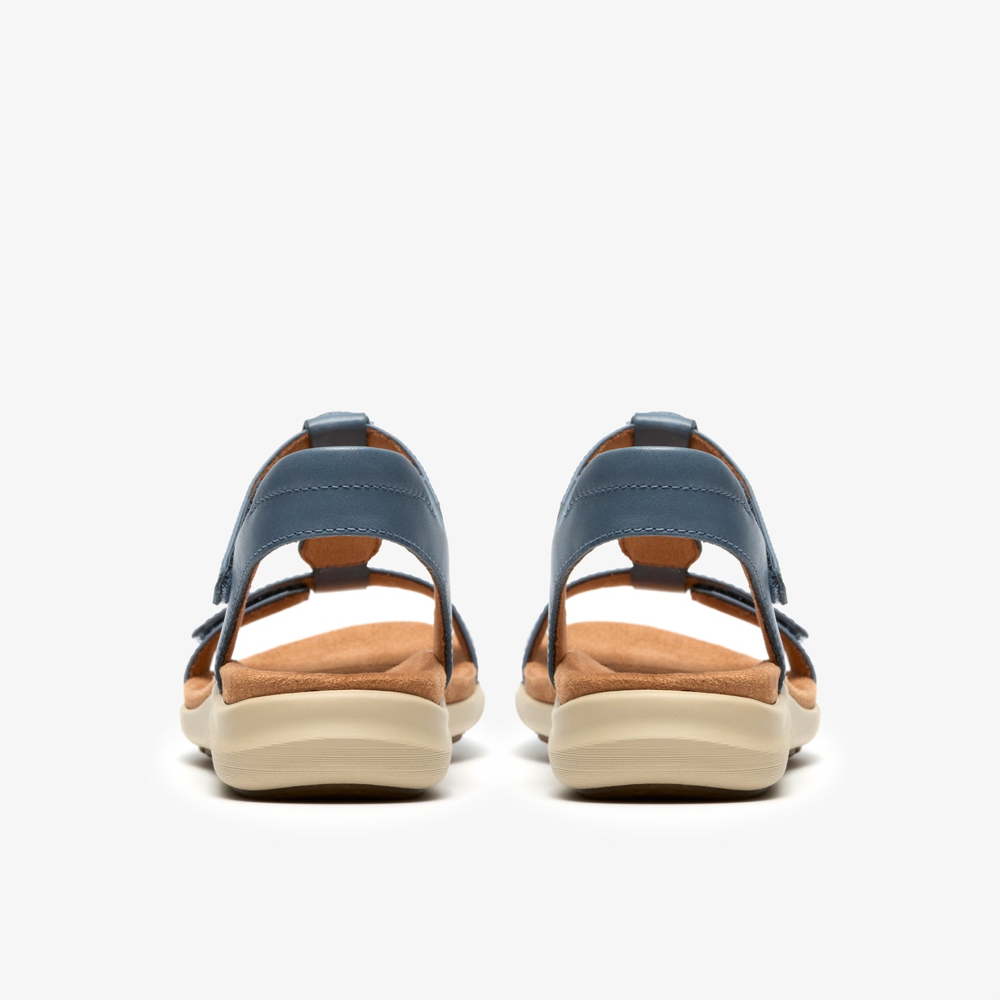 Pair of denim-colored leather sandals with tan insoles and cream soles, rear view.