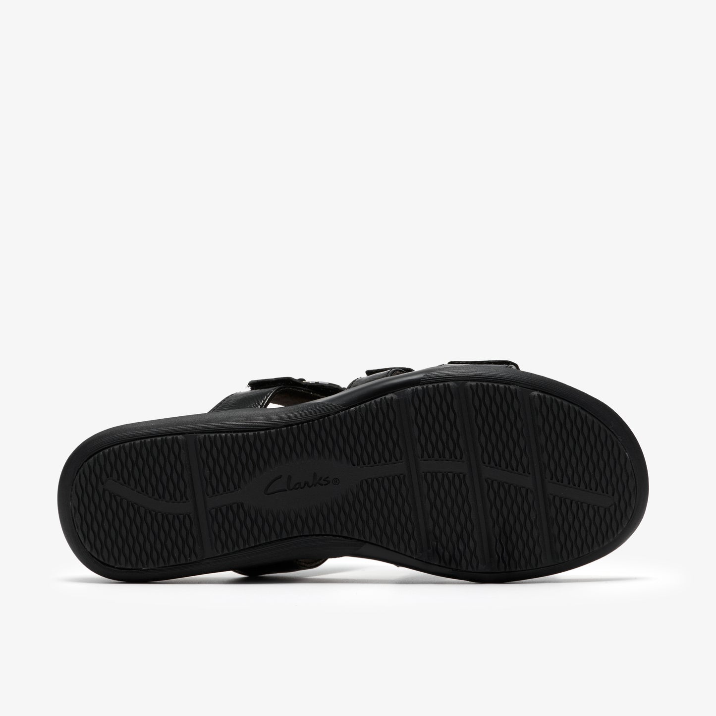 Black sandal showing the sole with a curved tread pattern.