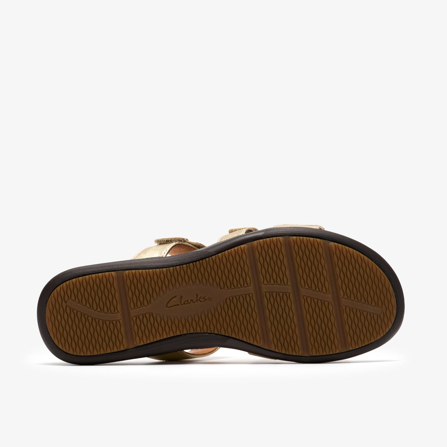 Bottom of a gold sandal with treaded brown sole and logo 'Clarks'.