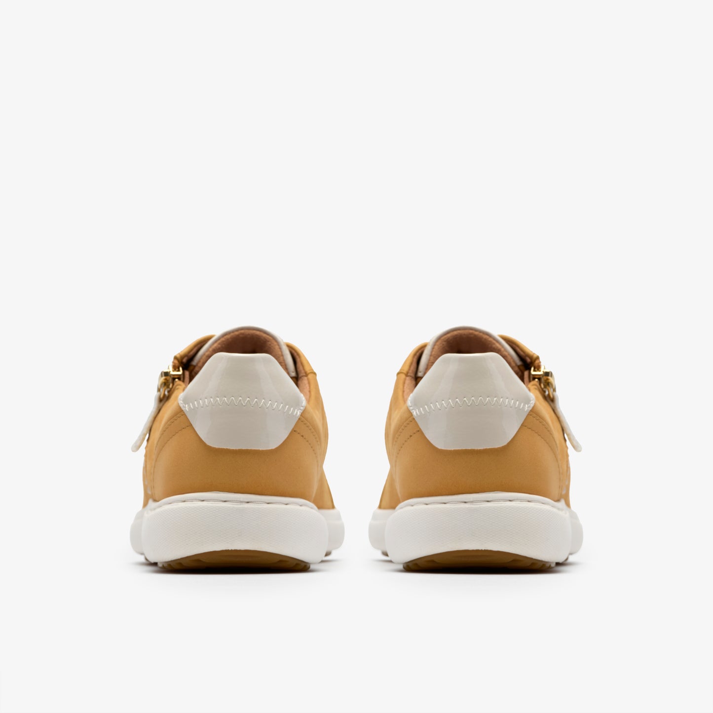 Rear view of tan sneakers with white soles and heel counters.