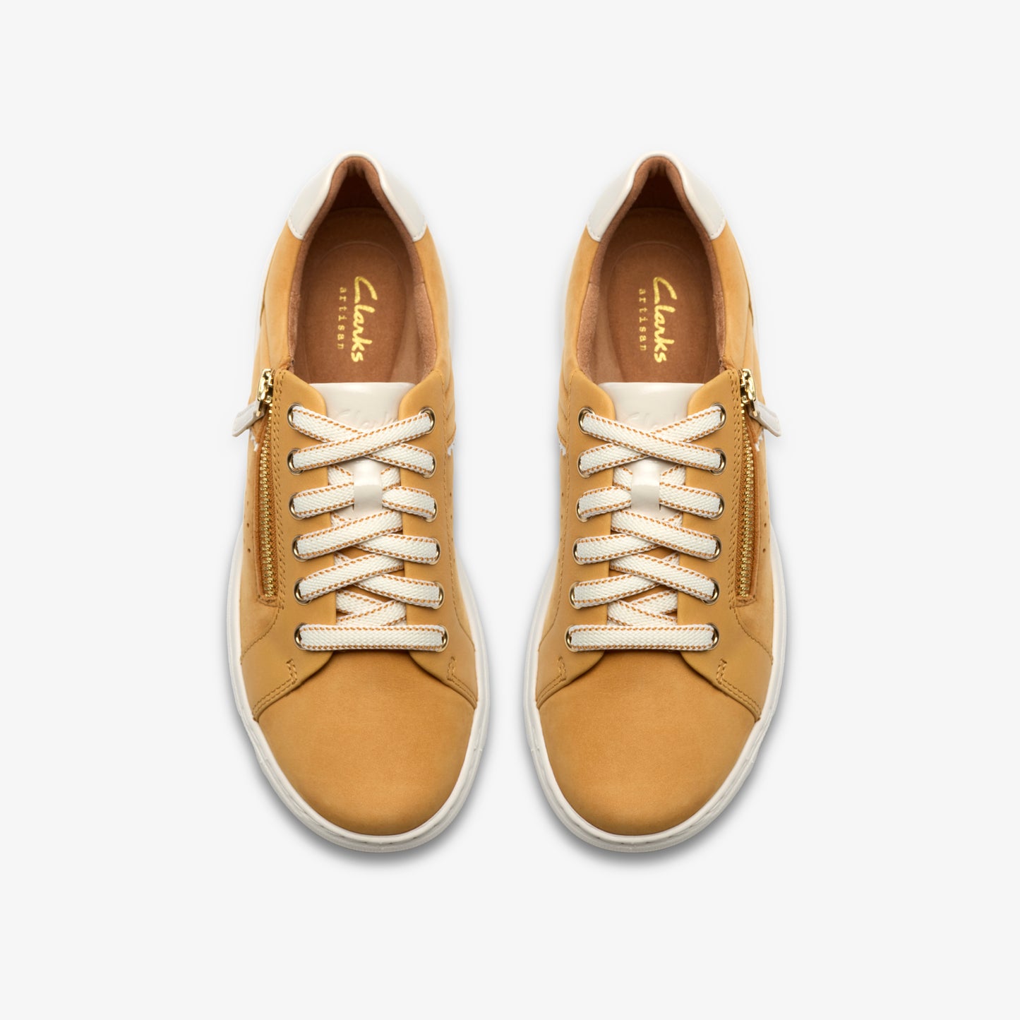 Overhead view of two tan-colored sneakers with white laces and gold zippers.