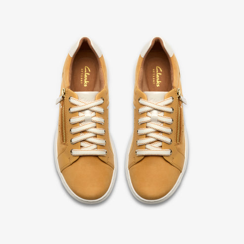 Overhead view of two tan-colored sneakers with white laces and gold zippers.
