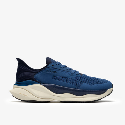 Blue sneaker with knit upper, cushioned midsole, and rubber outsole. The shoe features tonal accents and a streamlined silhouette. The word "CLARKS" is visible on the shoe's upper.