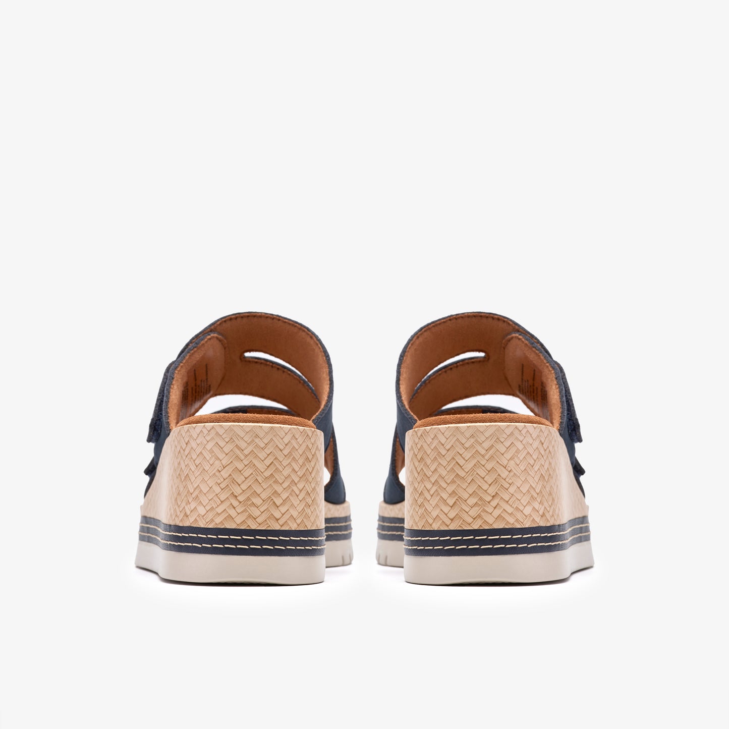 Rear view of two open-toed sandals with woven straw platform soles and dark-colored adjustable straps.