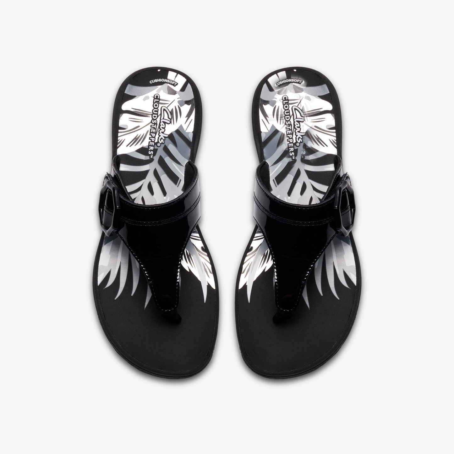 A pair of glossy black toe-ring sandals with a decorative buckle and a tropical leaf pattern on the footbed.