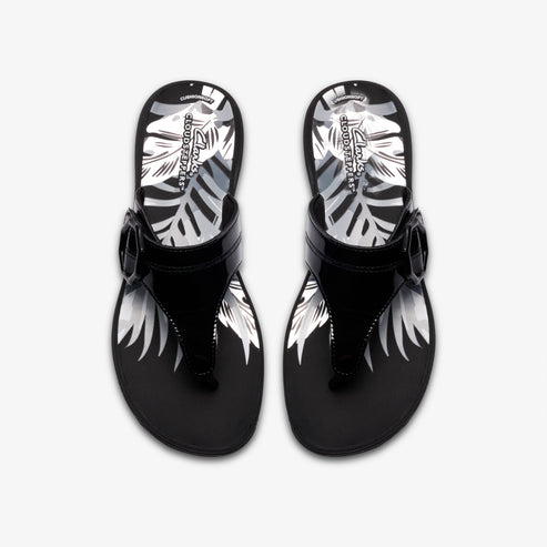 A pair of glossy black toe-ring sandals with a decorative buckle and a tropical leaf pattern on the footbed.