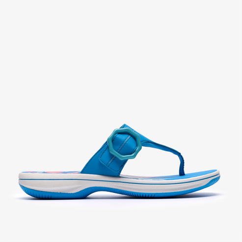 Side view of a bright blue sandal with a toe post and a flower-shaped strap detail.