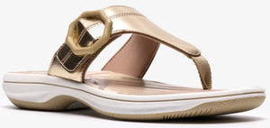 A shiny gold sandal with a ring and a thong toe.