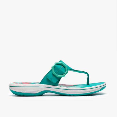 A bright teal sandal with a floral pattern on the insole and an ornamental buckle.