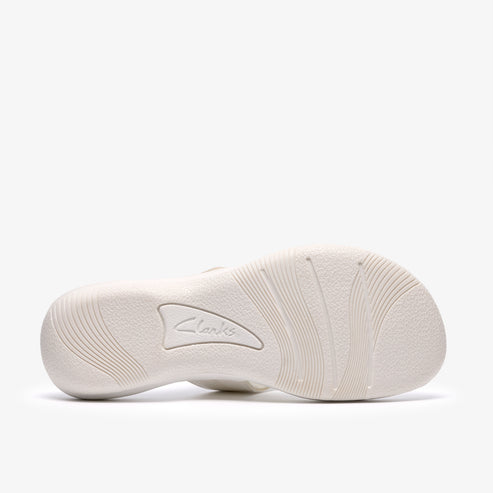 Bottom view of an off-white sandal showing the sole, which has a textured pattern. "Clarks" is embossed in the middle.