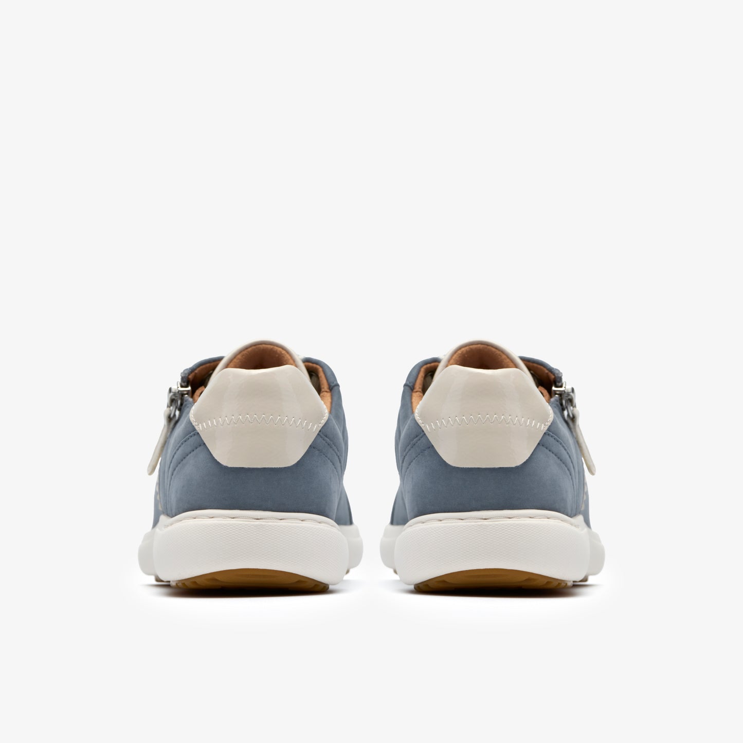 Rear view of two blue nubuck sneakers with white heel caps and soles. Sneakers are oriented front to back.